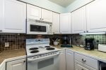 kitchen cabinets, range oven, microwave, tile back splash, tile counter tops, kitchen amenities